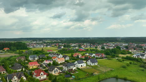 Aerial-of-a-suburban-neighborhood-with-modern-houses,-green-lawns,-and-a-backdrop-of-countryside