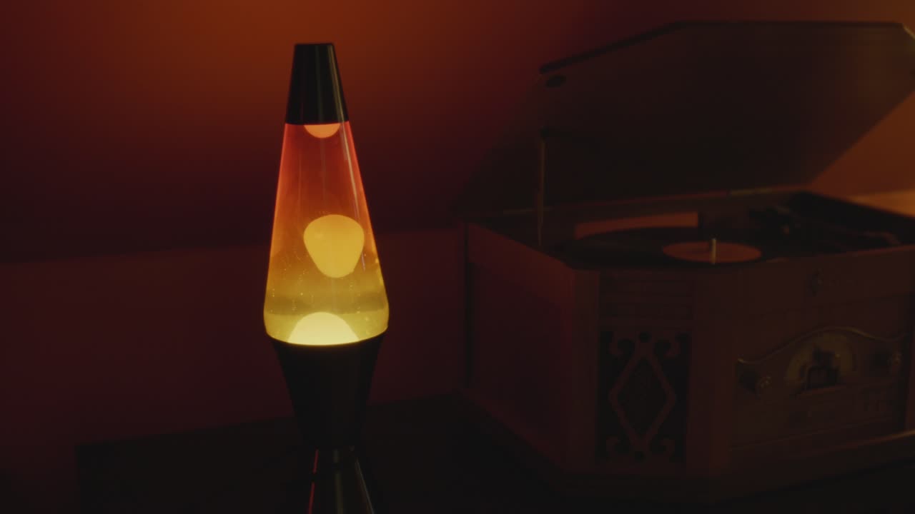 A lava lamp and record player in a warm and vintage setting. Orange lighting and bubbles create a retro atmosphere. Shot in 60 Frames for slow motion