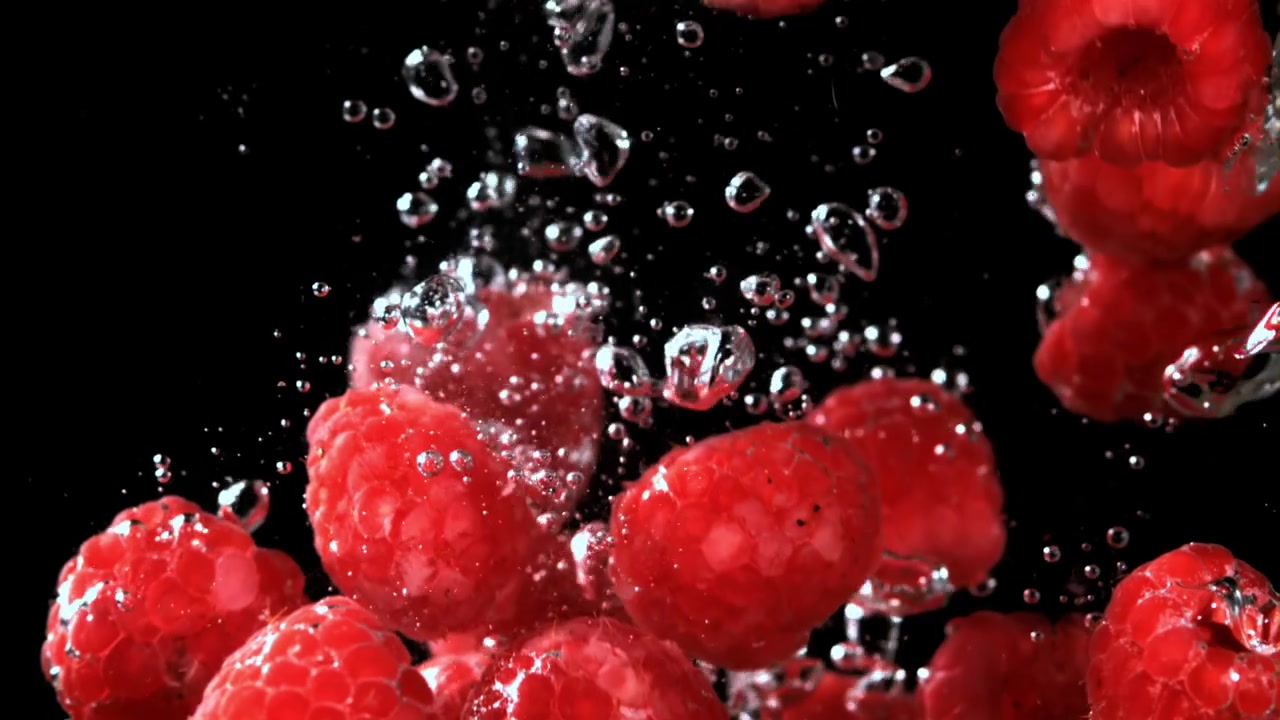 Fresh Red Raspberries Falling into Water in Slow Motion
