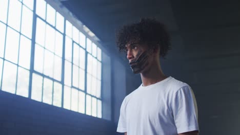 african american man with hand mark on their mouth standing in empty parking garage