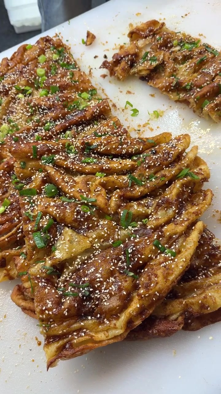 Chef che taglia una frittella croccante alle cipolle verdi su un tagliere