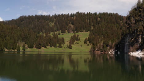 Flying-low-over-beautiful-lake-in-stunning-area-with-mountains-and-trees