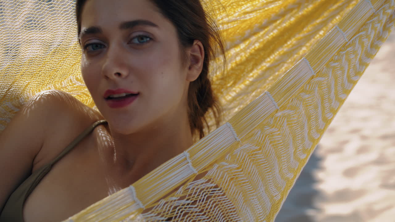 hermosa chica descansando en una hamaca en bikini de primer plano. mujer despreocupada mirando la cámara