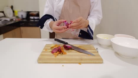 Close-up-shot-of-female-chef-preparing-and-peeling-red-onions-on-chopping-board