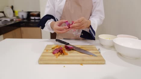 disparo en primer plano de una chef preparando y pelando cebollas rojas en una tabla de cortar