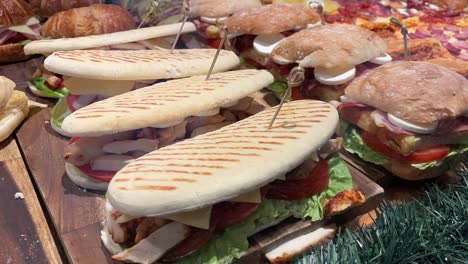 grilled sandwiches and subs with various toppings on a wooden plank