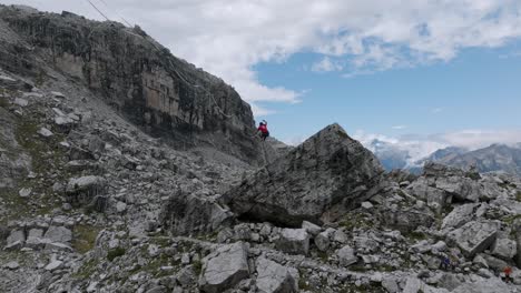 Person-jumping-on-slackline-in-Brenta-Dolomites-mountains-in-summer,-drone-tracking-shot