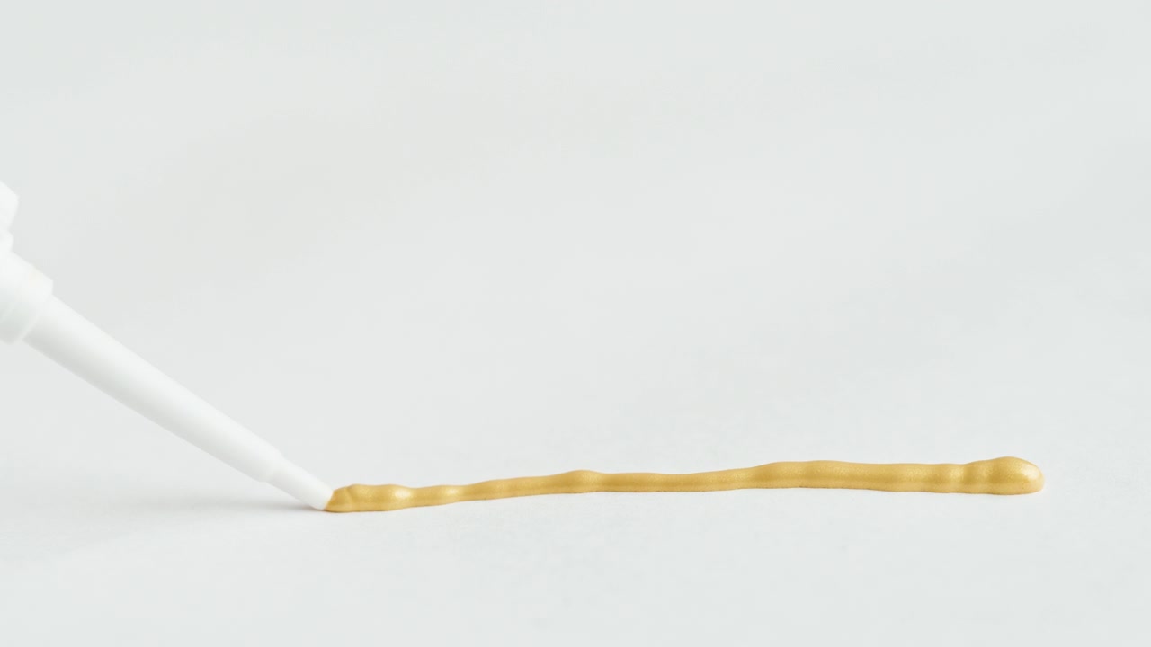 Close-up of Golden Liquid Being Dispensed from a Tube