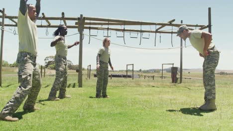 fit diverse group of soldiers doing press ups after jumping jacks on obstacle course in the sun