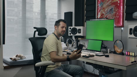 man using smartphone in a home music studio for video call or online recording session
