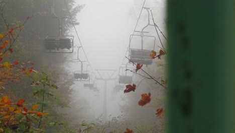 Revealing-shot-of-old-abandoned-rusty-chair-lift-hidden-in-autumn-forest-fog