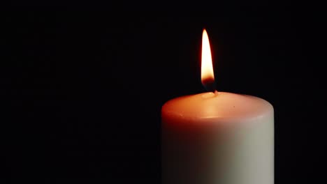 the showcases of colorful single candlelight on black background with the effect of light and slow motion