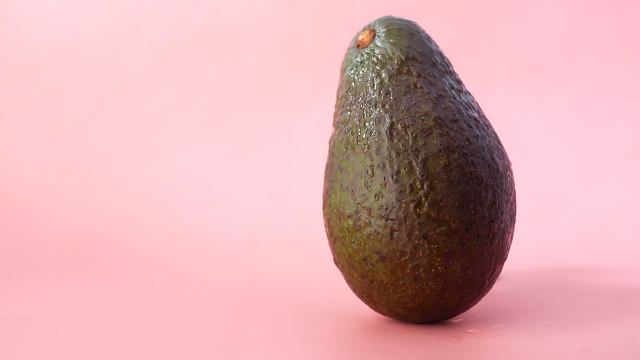 Un avocado su sfondo rosa