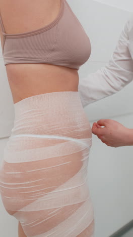 cosmetólogo deformando el vientre de la mujer con vendaje elástico máscara corporal anticelulita pérdida de peso