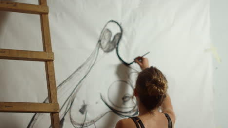 Inspired-woman-drawing-in-studio.-Talented-painter-using-black-paint-indoors.