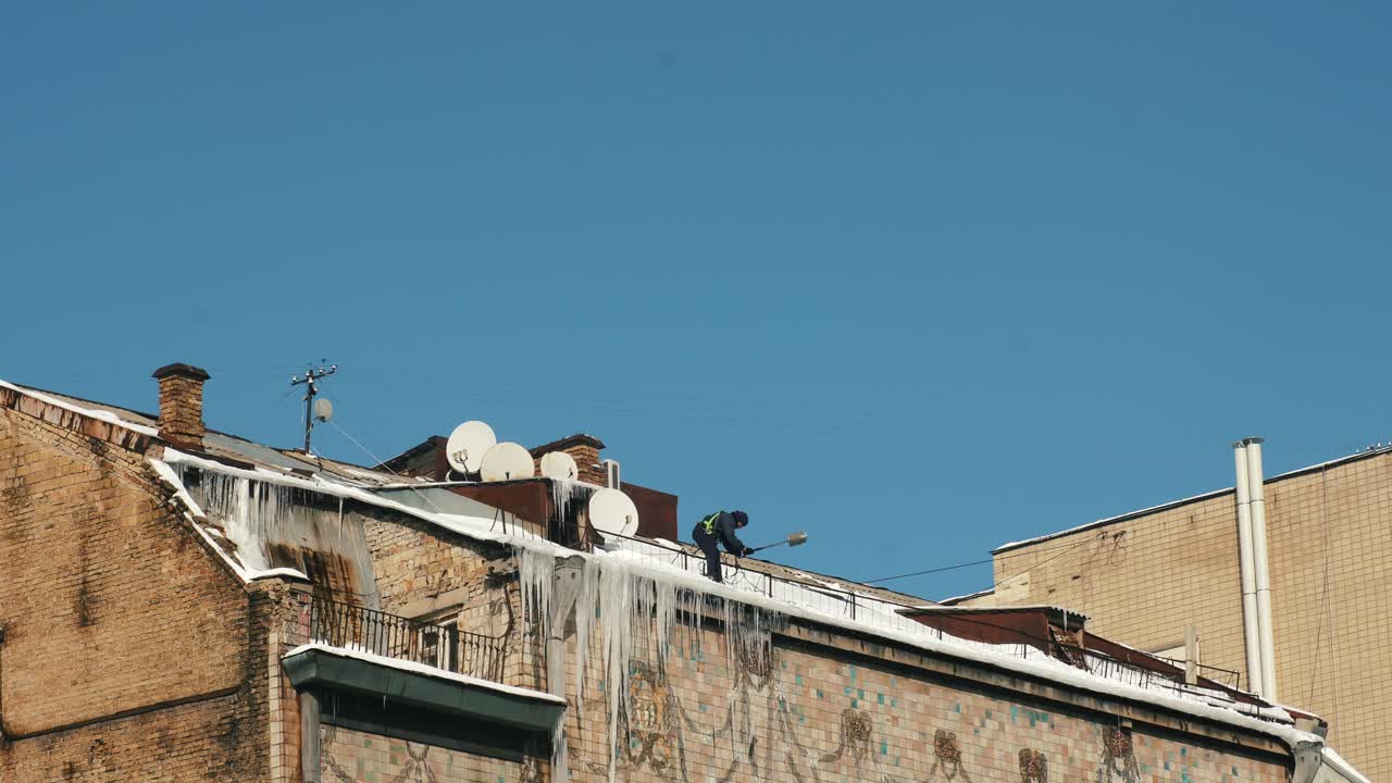 지붕 에서 눈 과 얼음 을 청소 하는 노동자