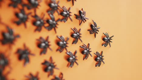 Close-up-of-multiple-spider-toys-with-copy-space-against-orange-background