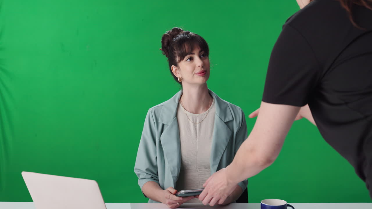Woman using tablet and laptop in front of green screen