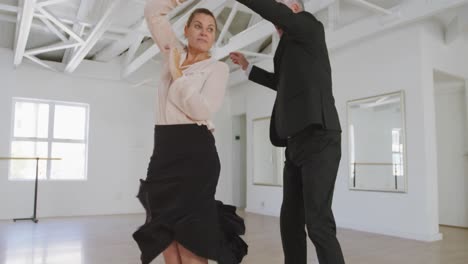 Caucasian-senior-couple-spending-time-together-dancing-in-a-ballroom