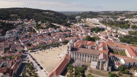 orbiting shot of mosteiro de alcobaça against cityscape and forest, portugal