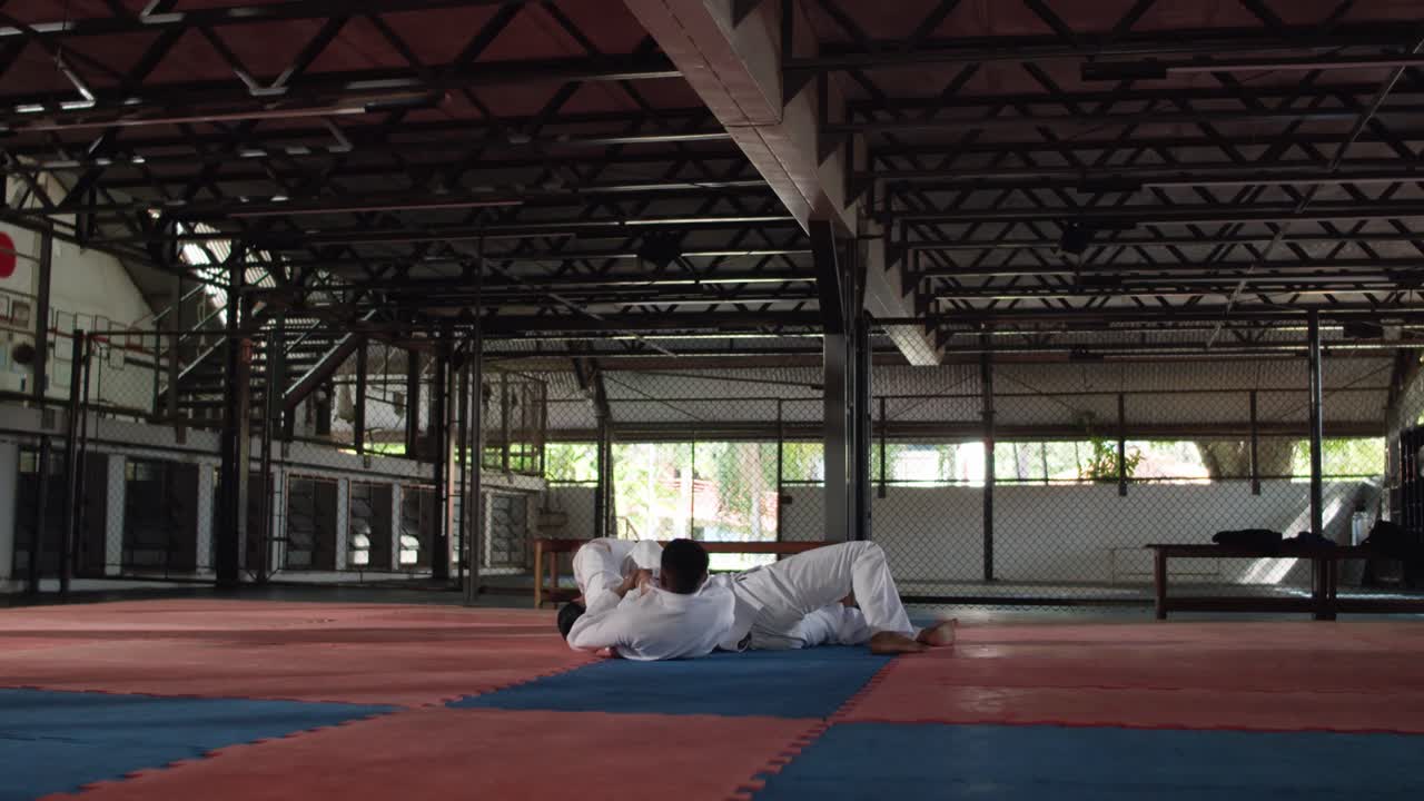 Two athletes demonstrate martial arts grappling techniques, including throws and ground work, during a training session