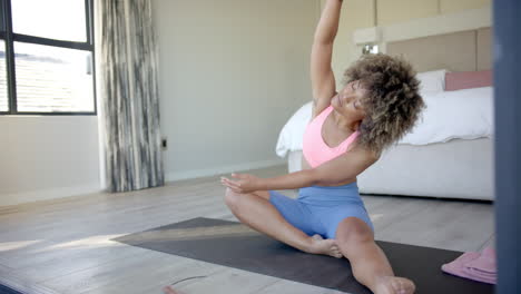 practicing yoga, woman stretching on yoga mat in bedroom for fitness