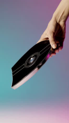 a hand holding a futuristic black object against a gradient background