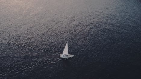 tilt down shot of sail boat cruising on calm ocean at mallorca island, aerial