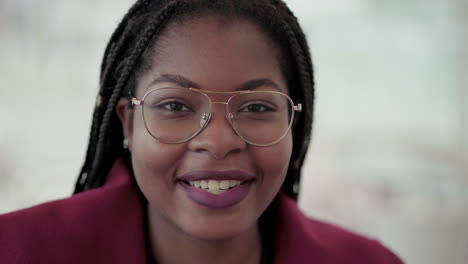 Close-up-shot-of-Afro-American-attractive-young-girl-with-plump-rose-lips-and-braids-in-aviator-eyeglasses-wearing-rose-coat