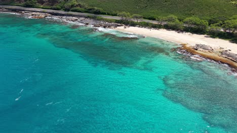 secluded sandy cove and turquoise water next to a coastal highway in oahu, hawaii