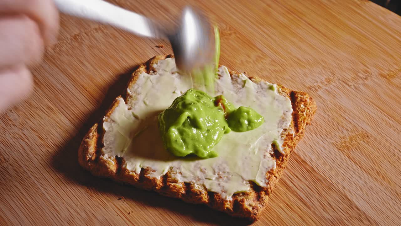 Toast integrale spalmato con formaggio e guacamole.