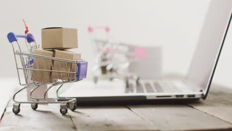 Boxes-in-shopping-trolley-beside-laptop-on-desk