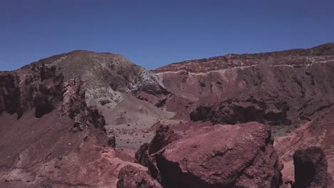 Drone-shot-revealing-Rainbow-Valley-red-sandstone-mountains-landscape,-Atacama-Desert,-Bolivia