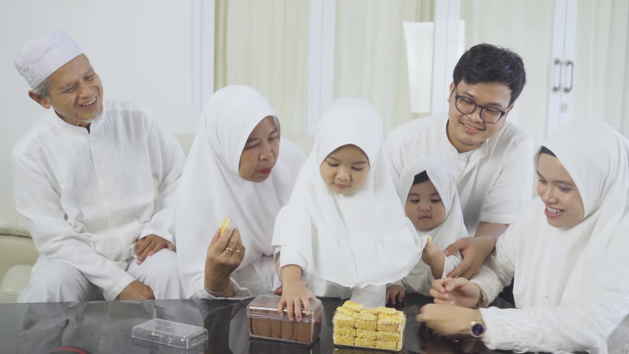 Keluarga Muslim makan kue di ruang tamu