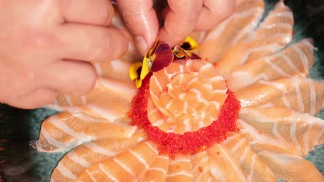 food plating - chef with putting fresh flowers on top of a sashimi salmon rose.