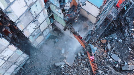 huge building being demolished with the help of a tractor. excavator with a long claw breaking walls of the ruined building. view from the above.