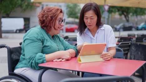 two women looking at a tablet at an outdoor cafe