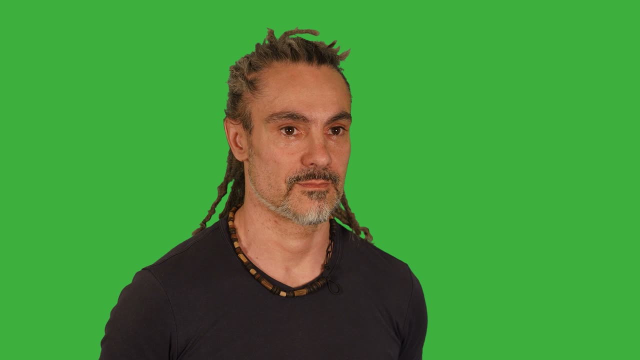 hombre de mediana edad luchando frente a una pantalla verde. preparándose para el combate y golpeando hacia la cámara. dreadlocks y camiseta negra.