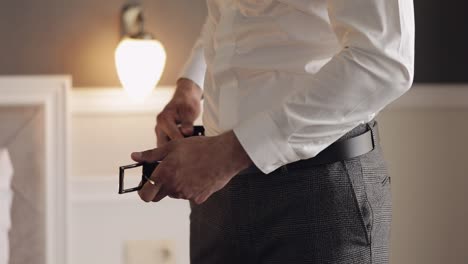 groom wears belt, man in white shirt puts belt on pants in wedding morning, businessman preparation