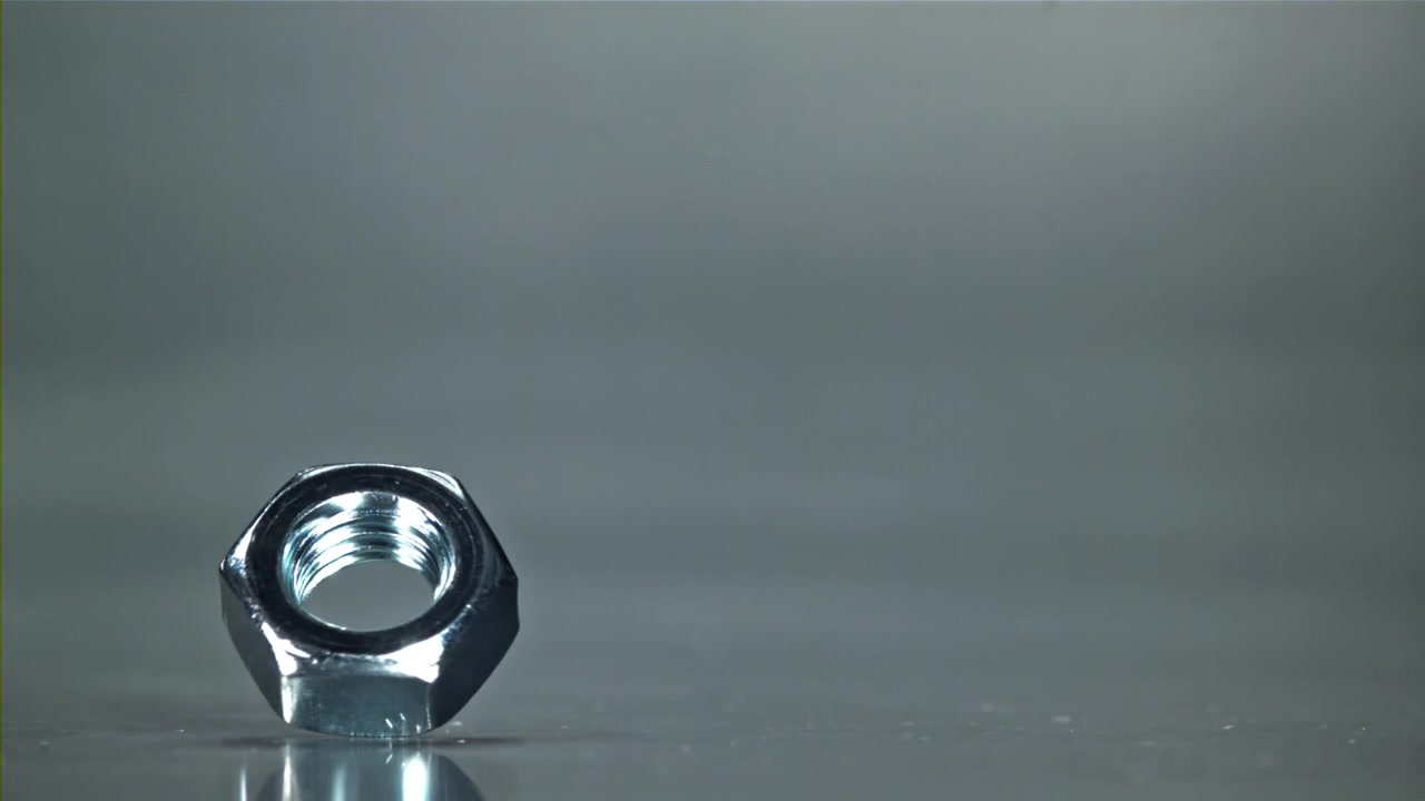 Slow Motion Close-Up of a Metal Nut Spinning and Wobbling