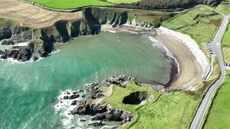 costa de irlanda imagen aérea estática de la carretera de la costa del cobre serpenteando su camino más allá de kilmurrin cove y su agujero de soplo en waterford en un día de verano