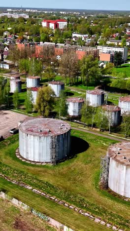 aerial view of rusty industrial storage tanks near a green suburban area in latvia