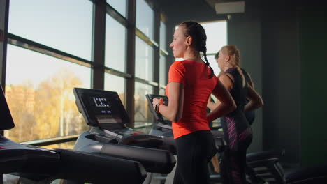 Süßes-Junges-Mädchen-Läuft-Auf-Einem-Laufband-Vor-Panoramafenstern-Im-Fitnessraum.-Fitnessstudio-Mit-Laufband-Und-Großen-Fenstern.