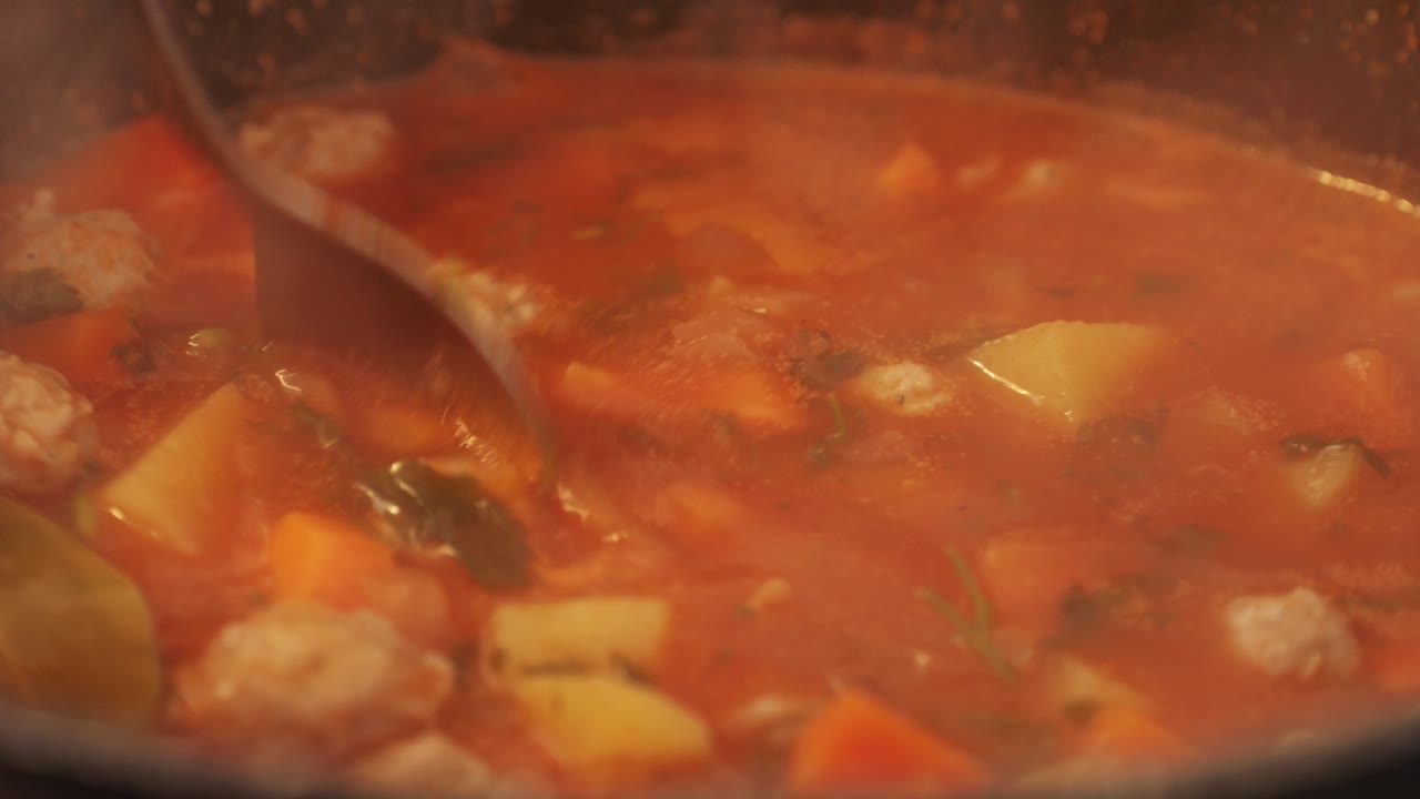 Turkish tomato soup with meatballs and vegetables close-up. Goulash soup with tomatoes, meatballs, potatoes, carrots, garlic and spices. High quality 4k footage