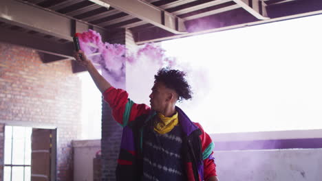 biracial man holding purple flare standing in an empty building