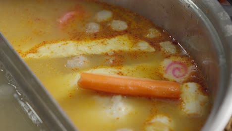 close-up of tom yum soup with kagosei narutomaki being cooked in pot