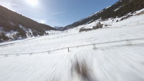 Racing-drone-over-Pyrenees-snowy-landscape-in-sunny-day,-Andorra