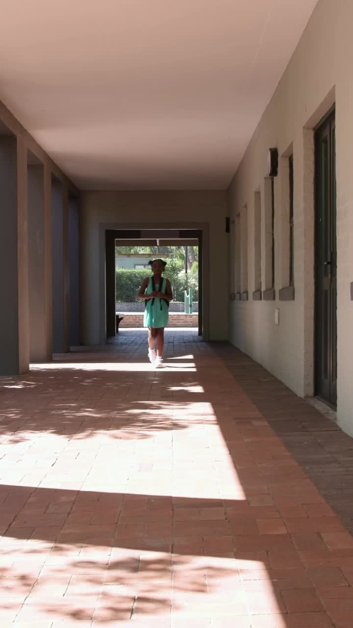 Vertical video: Door opening, pupil in mint dress walking through arcade adjusting backpack straps