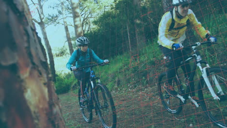 Two cyclists wearing helmets riding forest trail, showing animated health analytics and map overlay