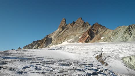 sobrevuelo aéreo sobre un glaciar cerca de arolla en valais, suiza con una vista panorámica desde los picos iluminados por el sol de aiguilles rouges iluminados al sol hasta las grietas en el hielo del glaciar